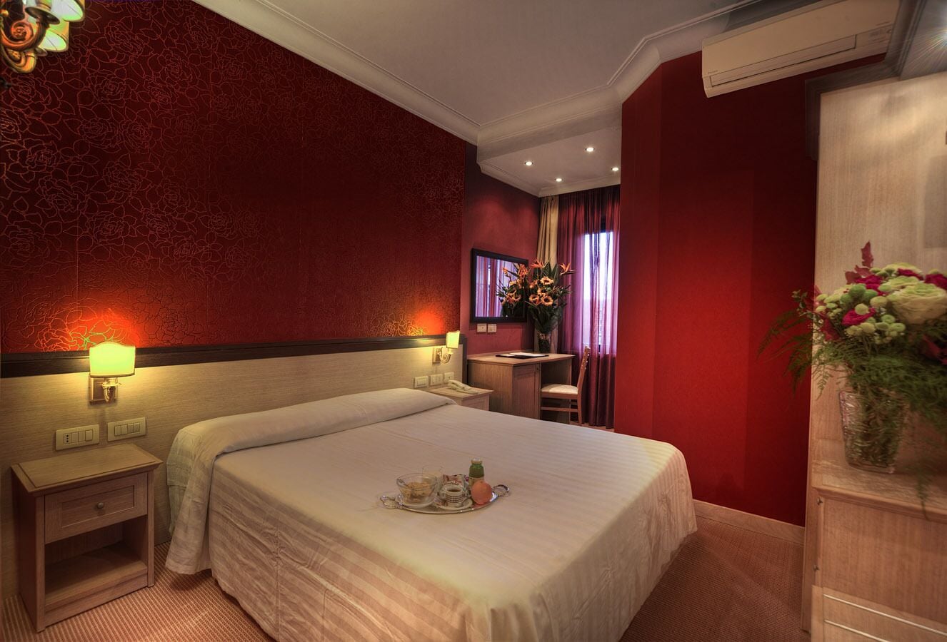 A hotel room with a large bed, bedside tables, a desk, and a chair.