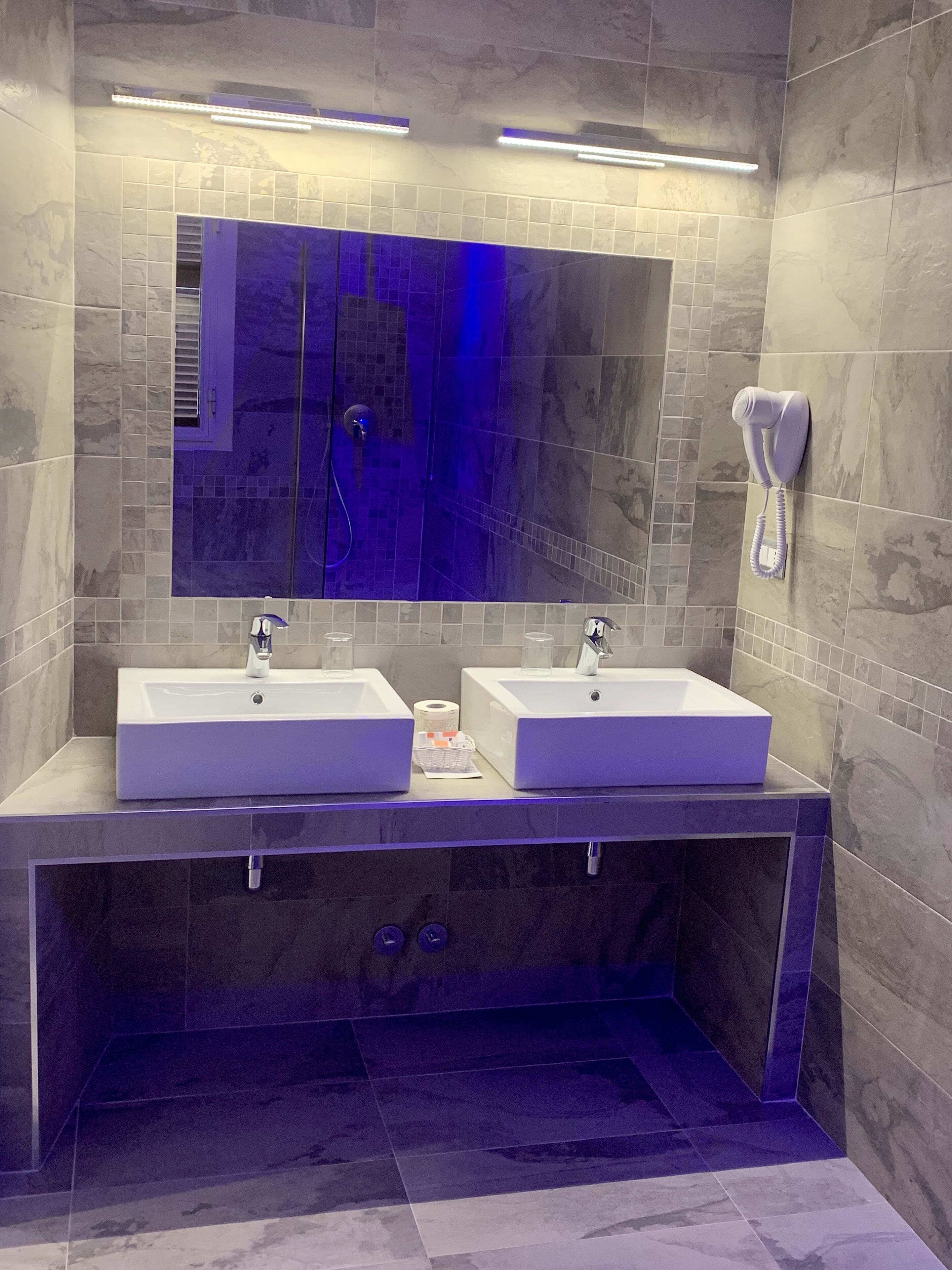 A modern bathroom with two sinks, a mirror, and a telephone.