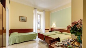 A hotel room with two single beds, a dining table with breakfast items, a mirror, and a potted plant. - Hotel Igea (Rome)