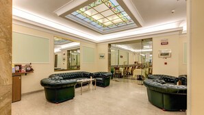 A spacious lobby with a high ceiling, a skylight, and a seating area with leather sofas. - Hotel Igea (Rome)