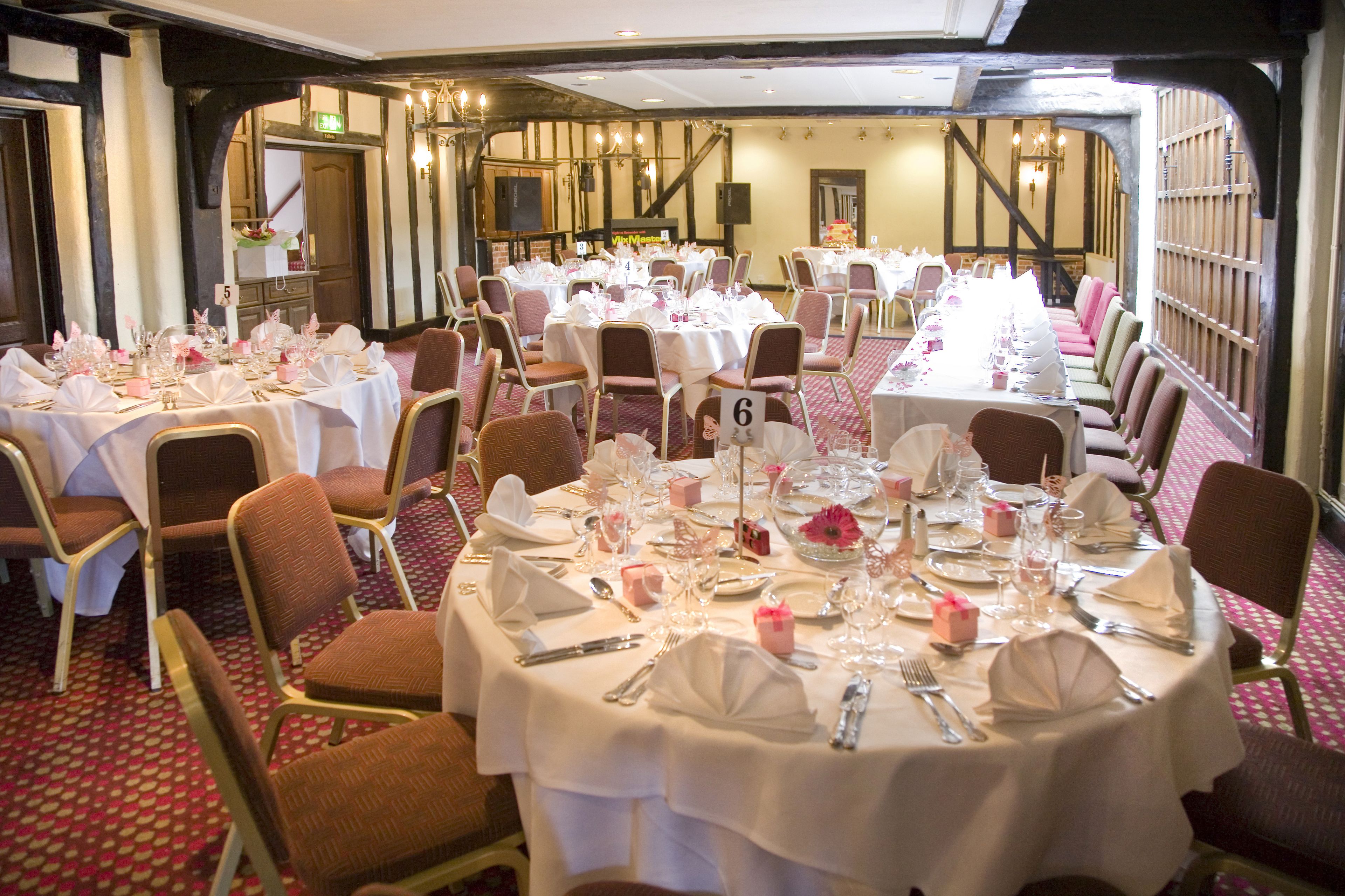 A banquet hall with multiple round tables set for dining, numbered placemats, and a classic interior design.