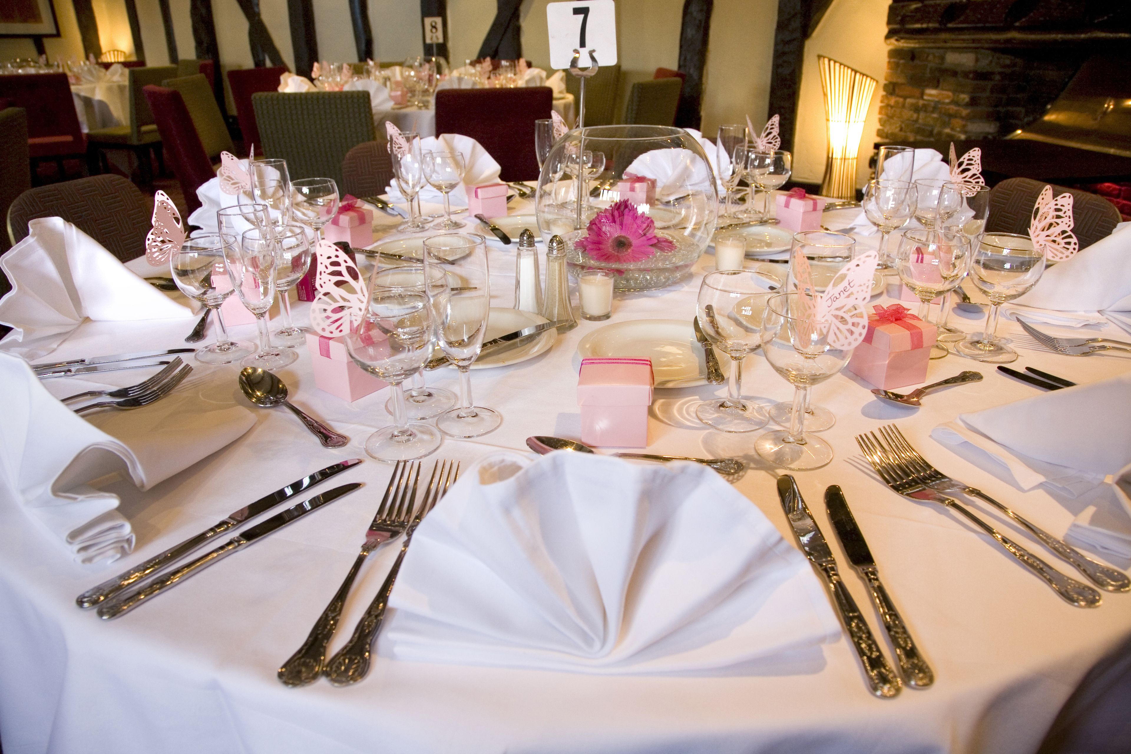 Une table dressée pour un dîner formel, avec plusieurs couverts comprenant assiettes, couverts et verres à vin.