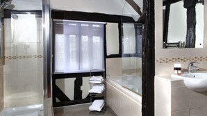 A bathroom with a glass shower enclosure, a bathtub, a sink, and a towel rack.