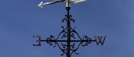 A weather vane with directional arrows and a compass rose on a metal pole.