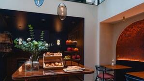A modern dining area with a wooden table, chairs, and a decorative wall. - Hôtel de Buci (Paris)