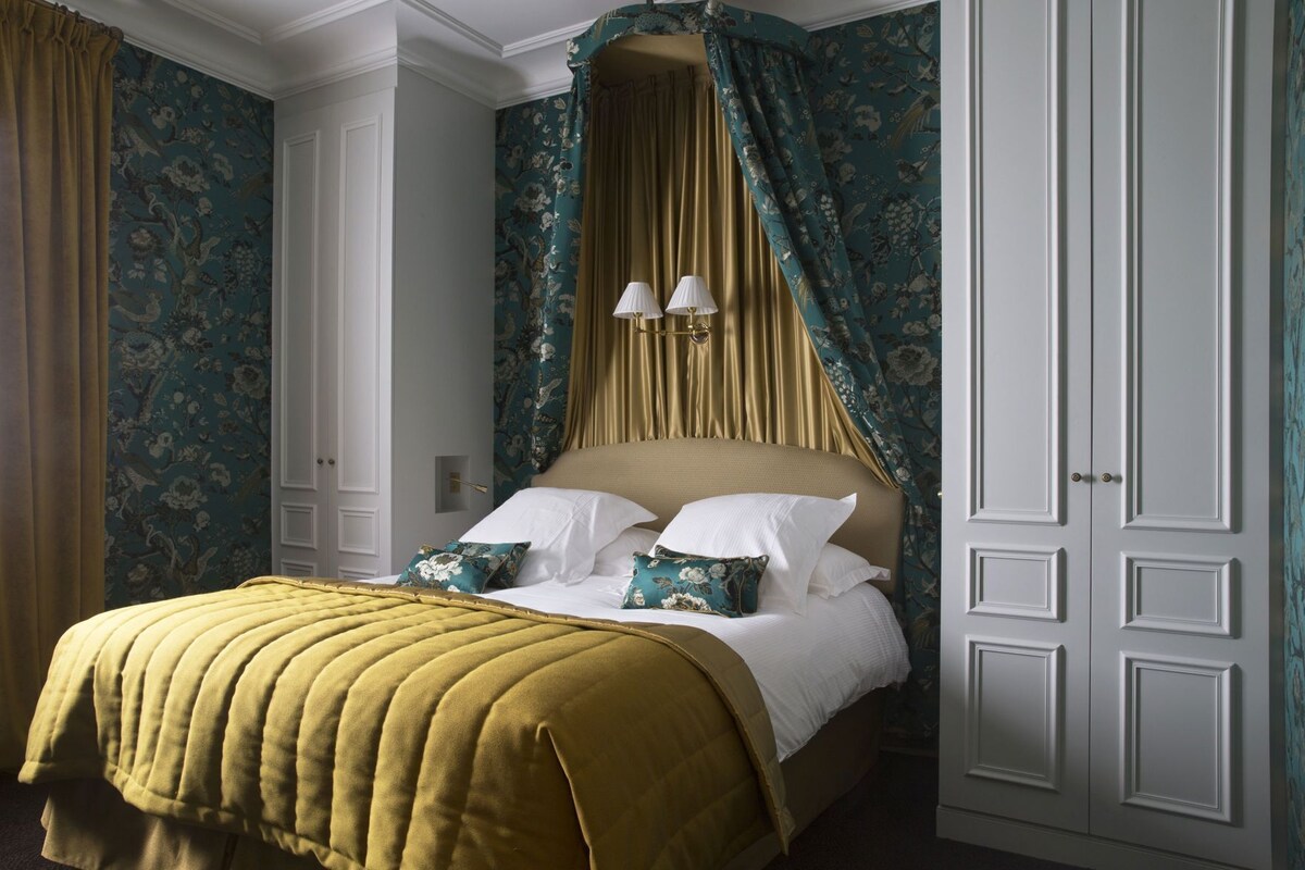 A bedroom with a bed, curtains, and a wardrobe.