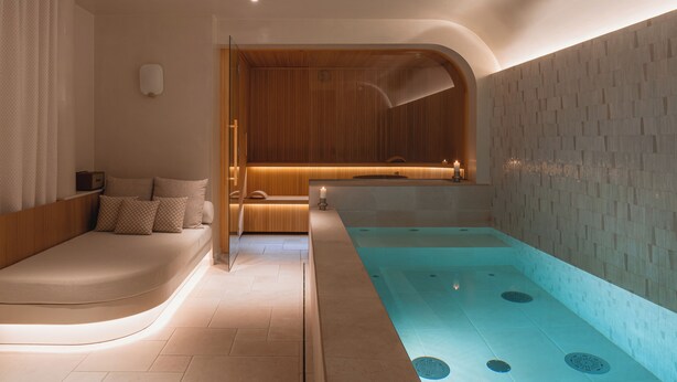 A modern spa room with a wooden bench, a massage table, and a large bathtub. - Hôtel de Buci (Paris)