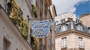 A hotel sign with a classic design, surrounded by lush greenery and traditional architecture. - Hôtel de Buci (Paris)