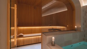A modern bathroom with wooden paneling, a glass-enclosed shower, and a bathtub with a candle. - Hôtel de Buci (Paris)