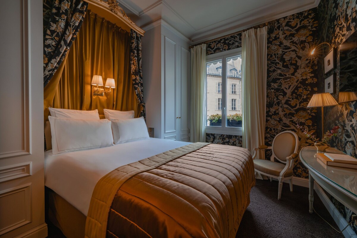 Una habitación de hotel con una cama grande, un escritorio y un ventanal con cortinas.