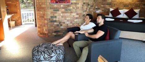 A cozy living area with a brick wall, a sofa, a coffee table, and a wooden chair.