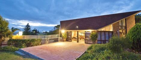 A modern building with a flat roof and large windows, surrounded by a landscaped garden.