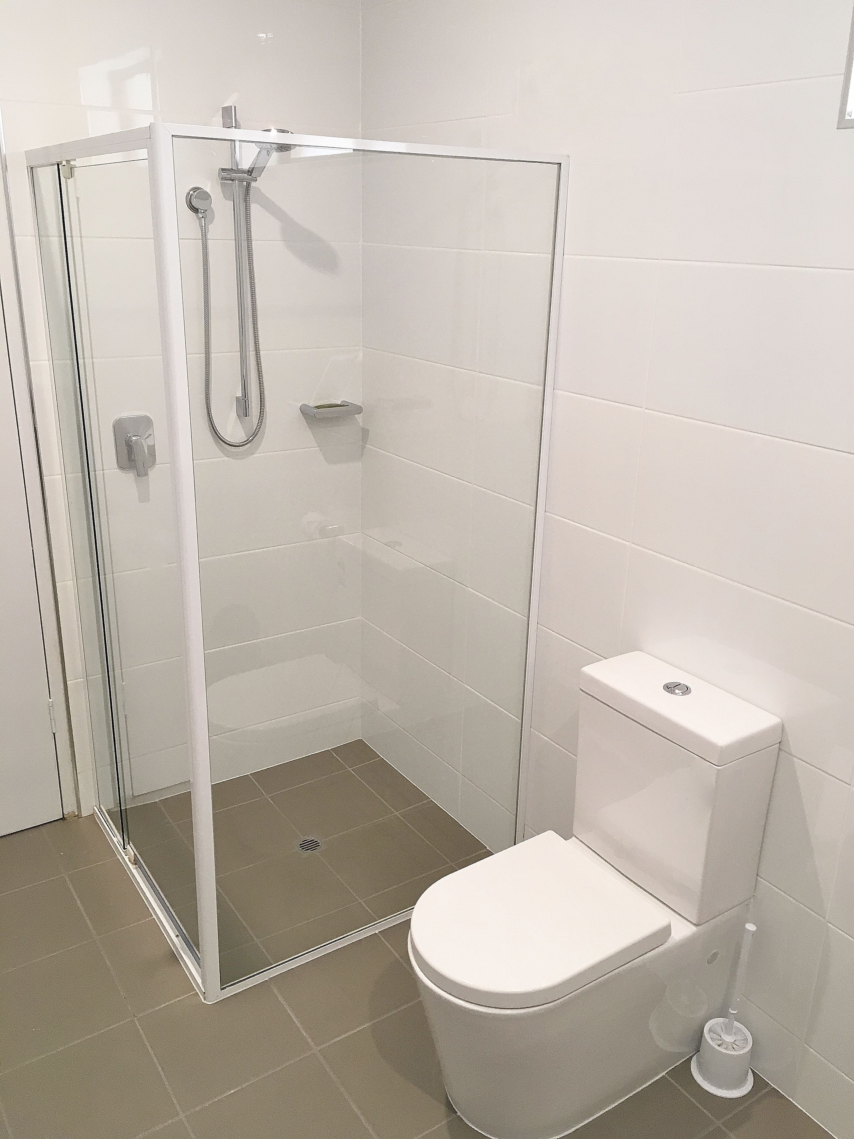 A modern bathroom with a glass-enclosed shower, a white toilet, and a bidet.