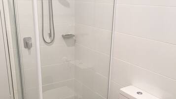 Un baño moderno con ducha de vidrio, inodoro blanco y bidé.