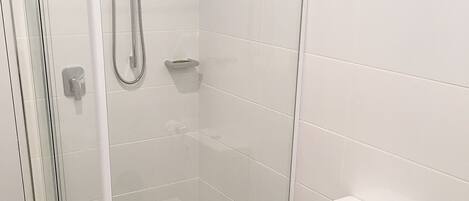 Ein modernes Badezimmer mit einer Duschkabine, einer weißen Toilette und einem Bidet.