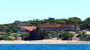 Propiedad costera con un edificio grande, una playa y abundante vegetación.