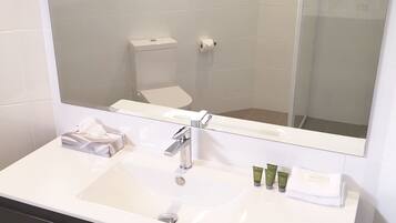 Un baño con un lavamanos blanco, un espejo y un inodoro.
