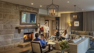 A cozy living room with a stone fireplace, comfortable seating, and a modern chandelier.
