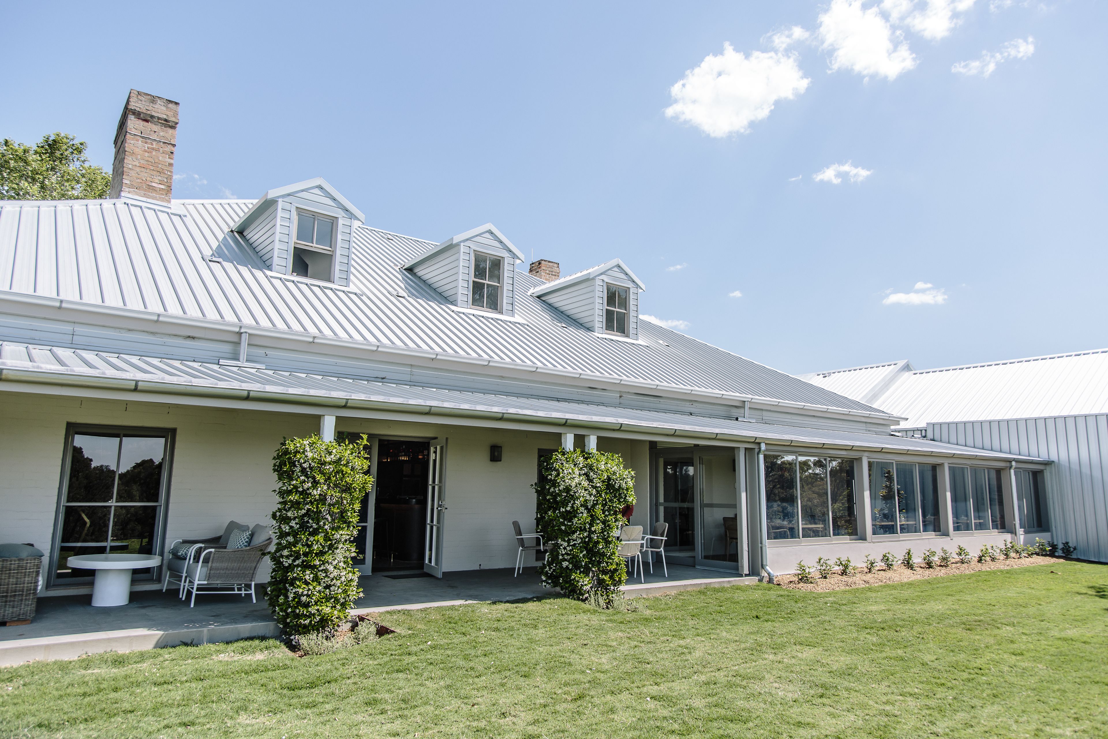 A modern house with a covered patio, a brick chimney, and a well-maintained lawn.