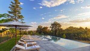 A swimming pool with lounge chairs and umbrellas, surrounded by a fence and trees. - Spicers Guesthouse (Pokolbin)