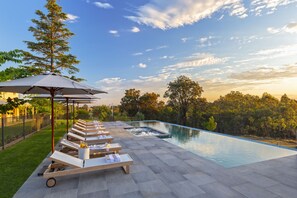 Een buitenzwembad, ligstoelen bij het zwembad