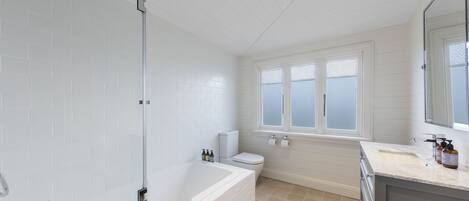 A modern bathroom with a glass-enclosed shower, a freestanding bathtub, a toilet, and a vanity with a mirror.