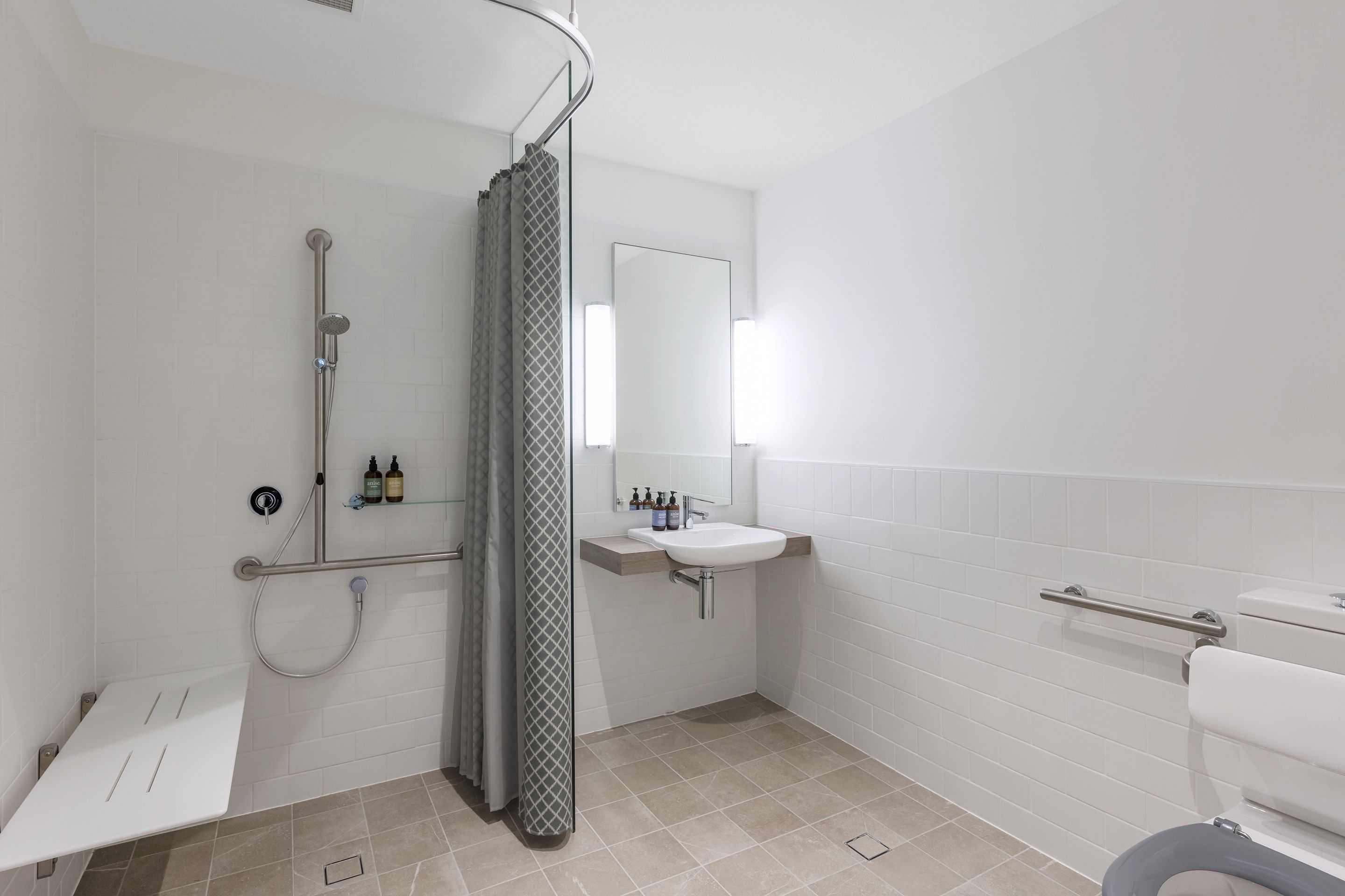 A modern bathroom with a shower, toilet, and sink.