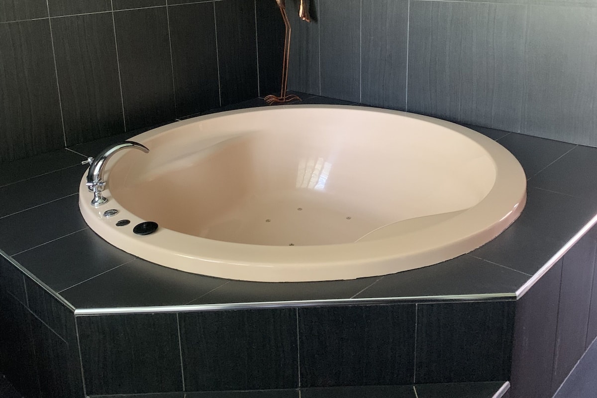 A modern bathroom with a freestanding bathtub, dark tiled walls, and a sleek design.