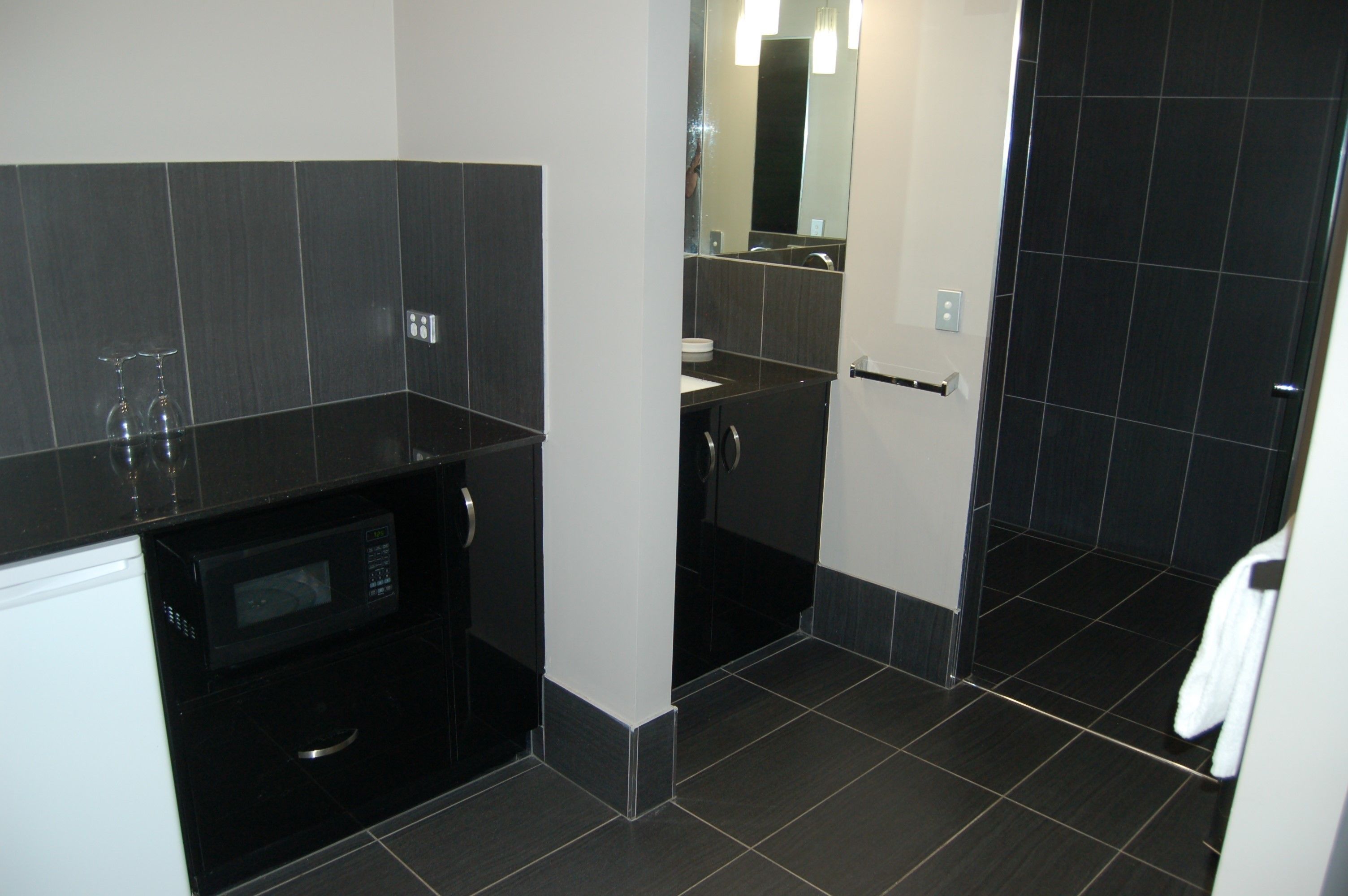 A modern bathroom with a black countertop, a sink, and a mirror.