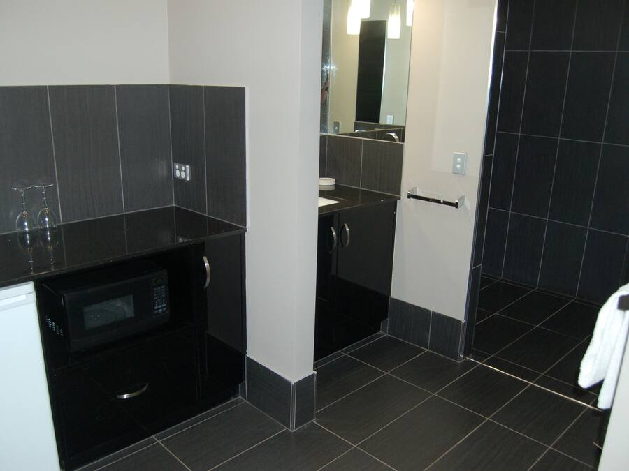 A modern bathroom with a black countertop, a sink, and a mirror.