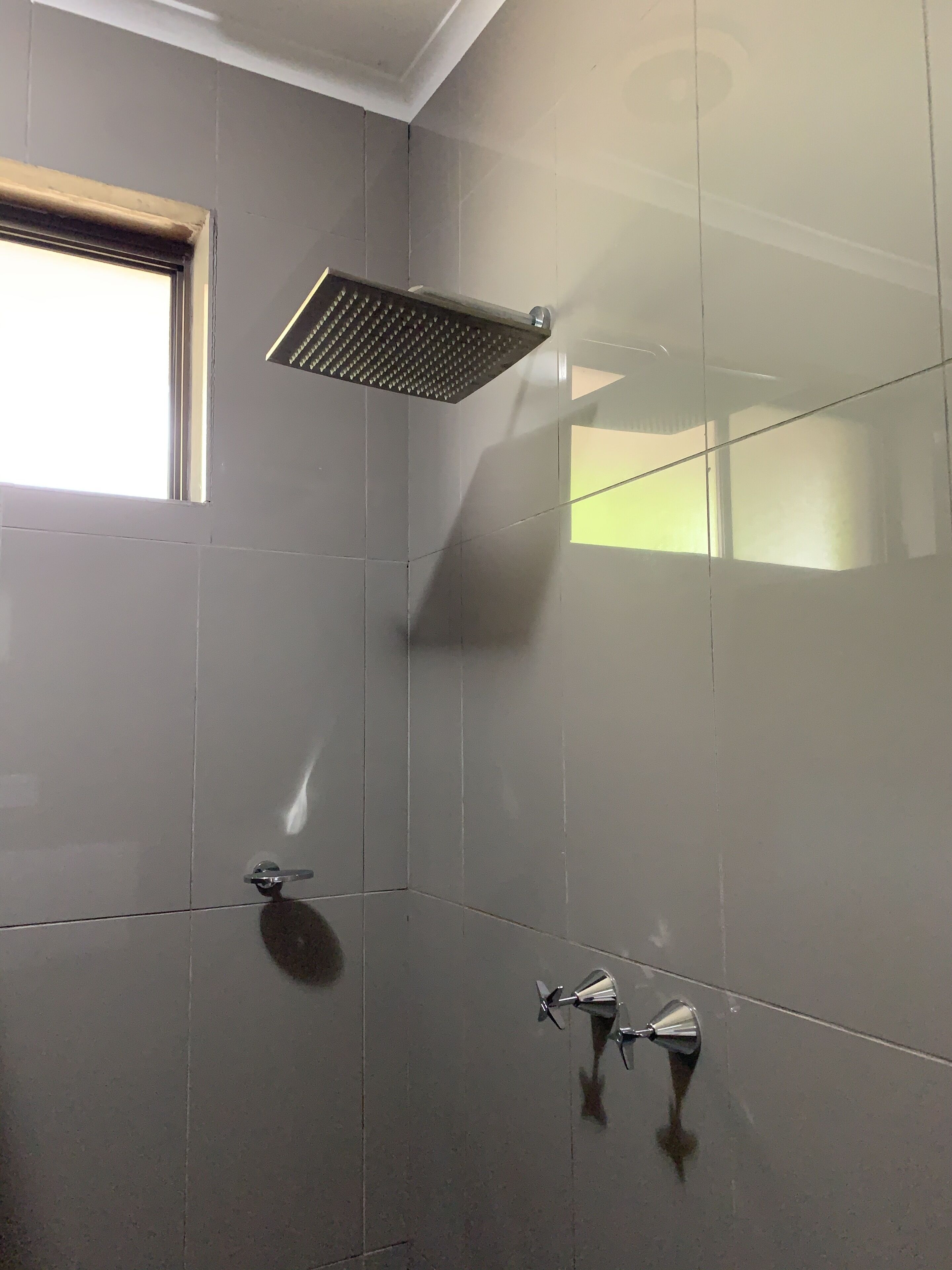 Un baño con ducha, ventana y espejo.