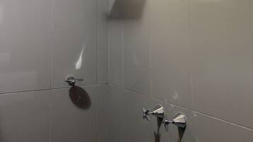 Un baño con ducha, ventana y espejo.