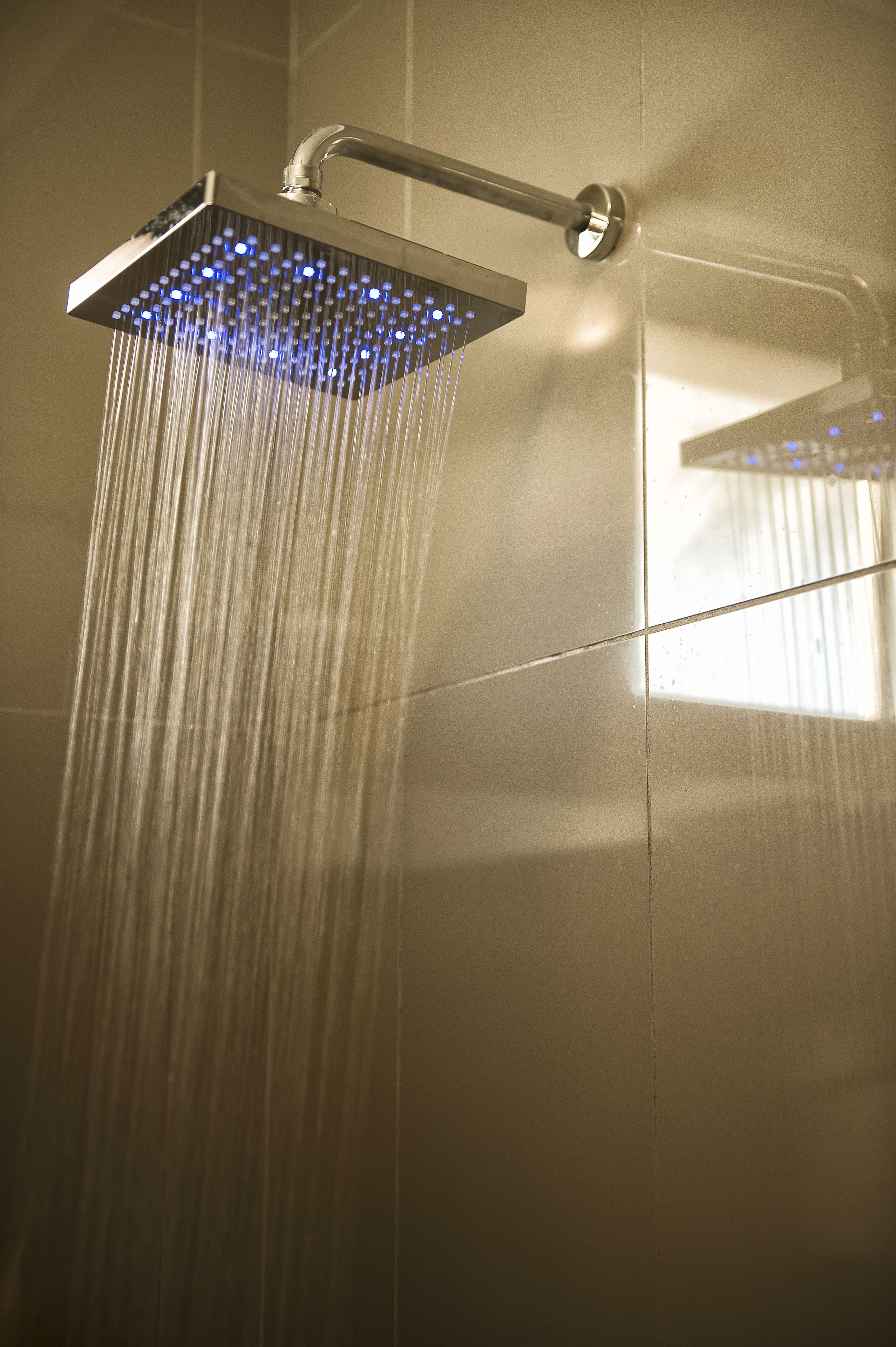 Een moderne douchekop met een vierkant ontwerp en blauwe LED-verlichting, water stroomt eruit.