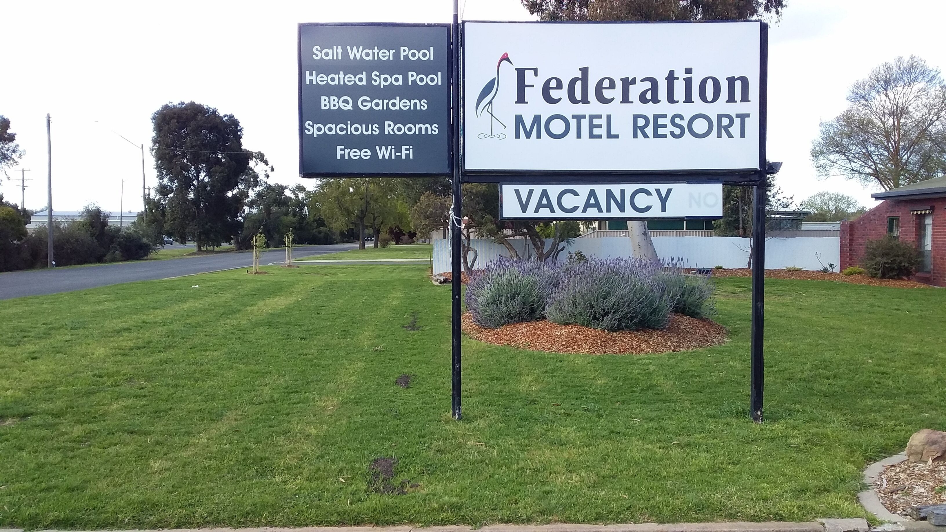 A motel sign with amenities including a saltwater pool, heated spa pool, BBQ gardens, spacious rooms, and free Wi-Fi.
