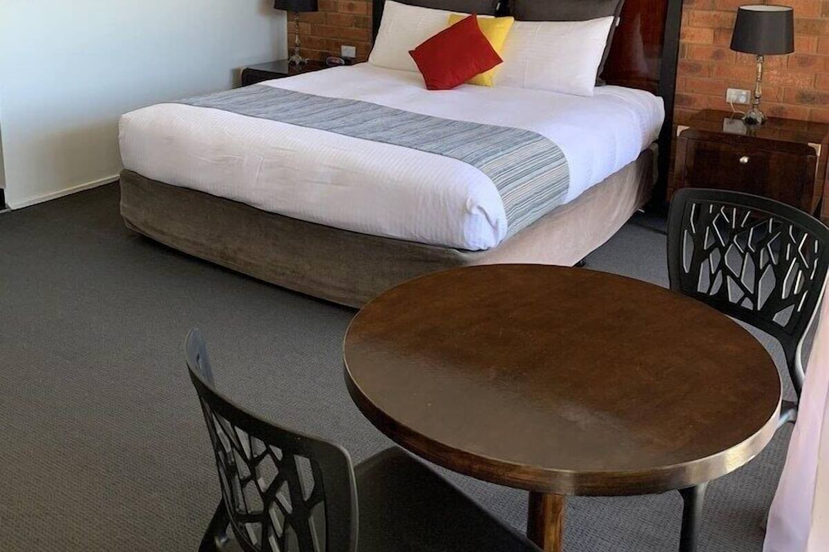A hotel room with a bed, two bedside tables, a round table, and two chairs.
