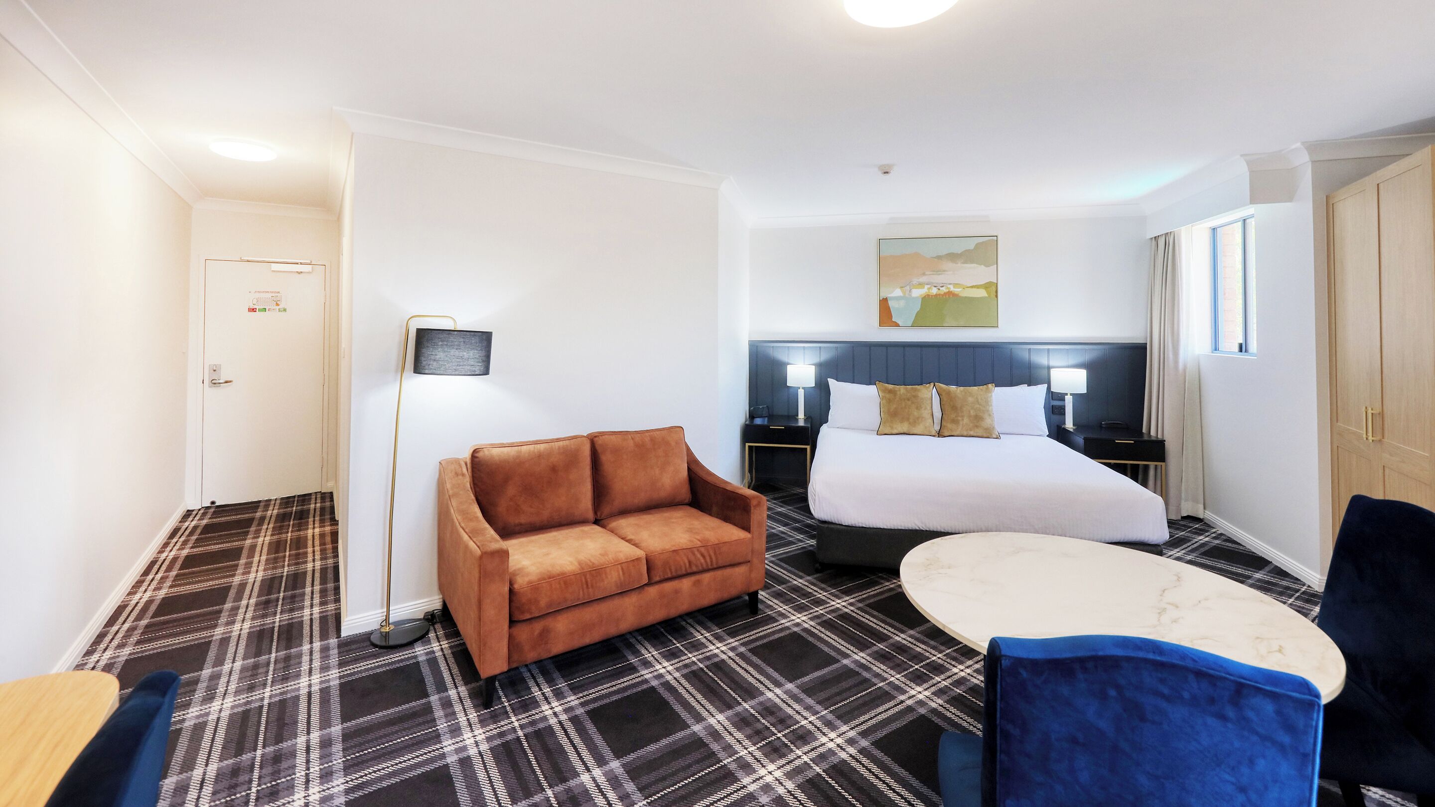 A hotel room with a bed, a sofa, a desk, and a chair.