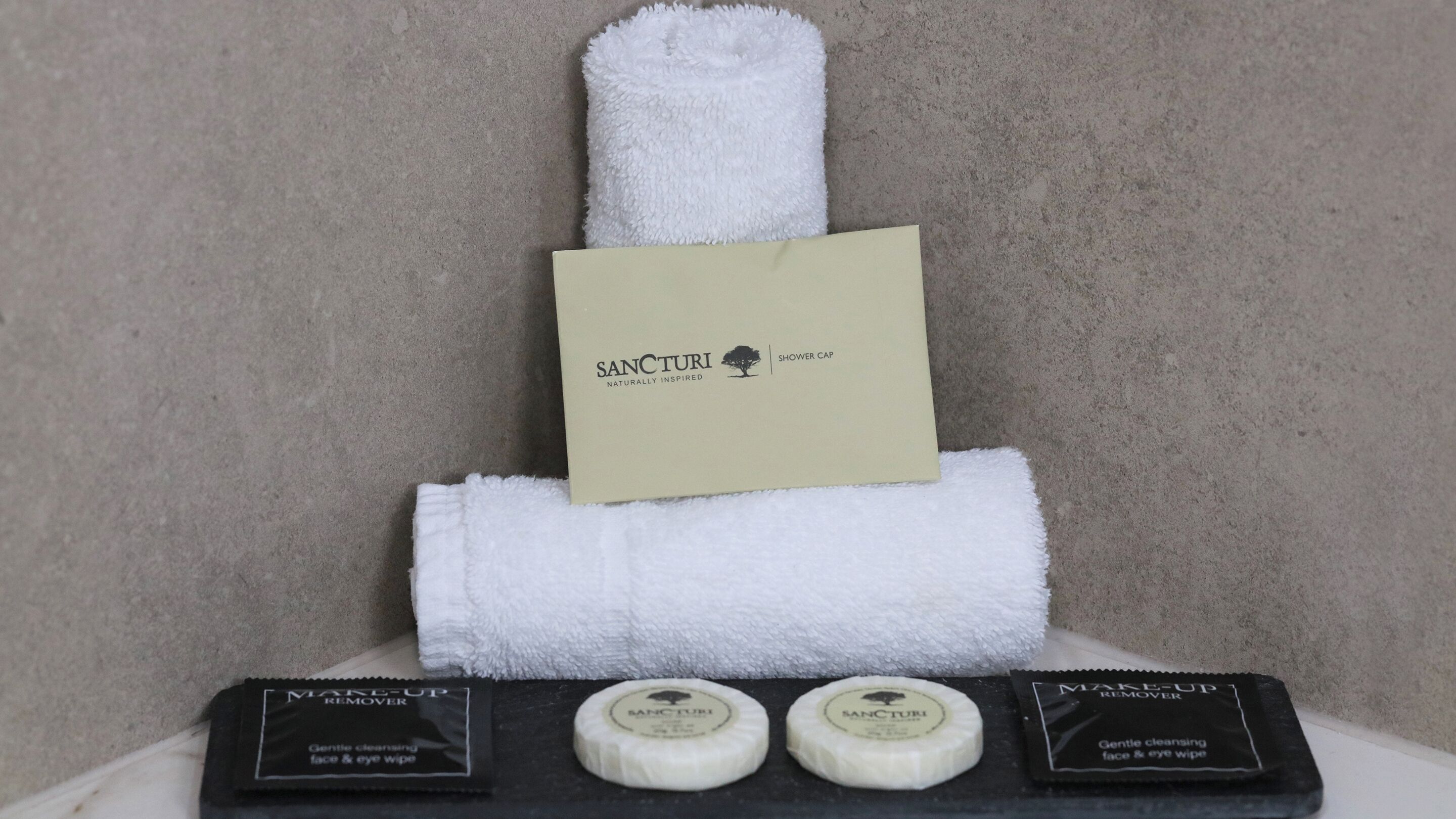 A display of Sanctuary brand shower cap, face and eye wipe, and makeup remover.