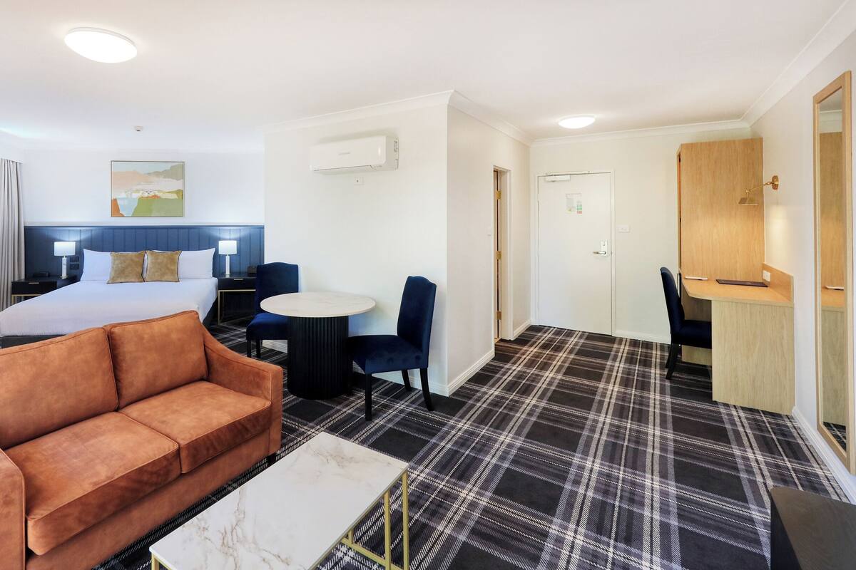 Une chambre d’hôtel avec un lit, un canapé, un bureau et une chaise.