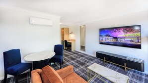 A hotel room with a TV, a dining table, two chairs, a sofa, a small desk, and a bed. - Dubbo RSL Club Motel (Dubbo)