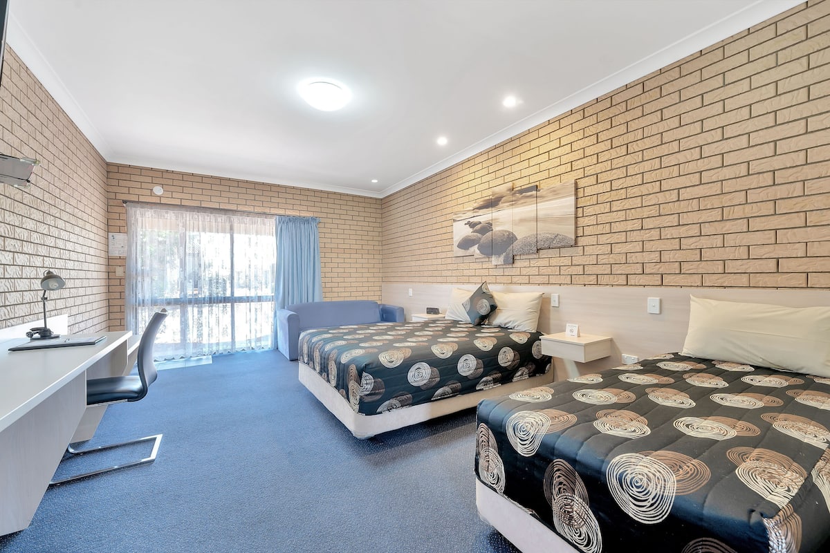 Una habitación de hotel con dos camas, un escritorio y una silla.