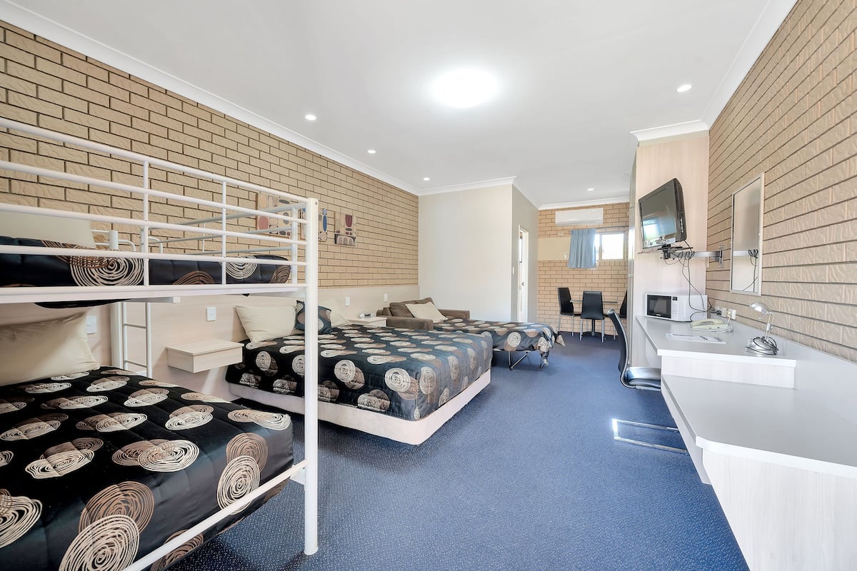 Una habitación de hotel con literas, un escritorio y una televisión.