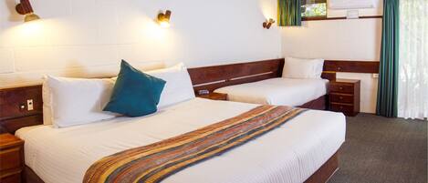 A hotel room with two beds, wooden headboards, white bedding, and a striped throw blanket.