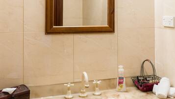 A bathroom with a marble sink, a wooden-framed mirror, and a small basket with toiletries.