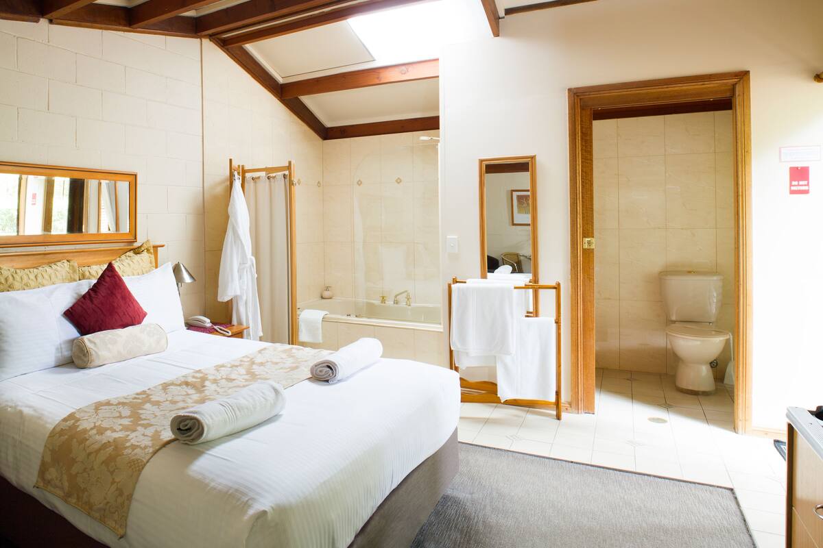 A hotel room with a large bed, a bathroom with a bathtub, and a toilet.