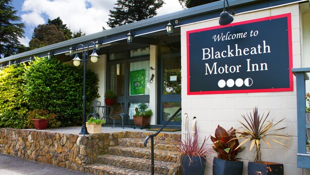 The exterior of Blackheath Motor Inn with a welcome sign, stone steps, potted plants, and a covered porch area. - Blackheath Motor Inn (Blackheath)