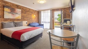 A hotel room with a large bed, a desk, a chair, a TV, and a balcony with curtains. - Comfort Inn Dubbo City (Dubbo)