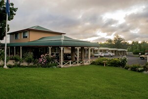 Un hotel con zona exterior cubierta, aparcamiento y césped.