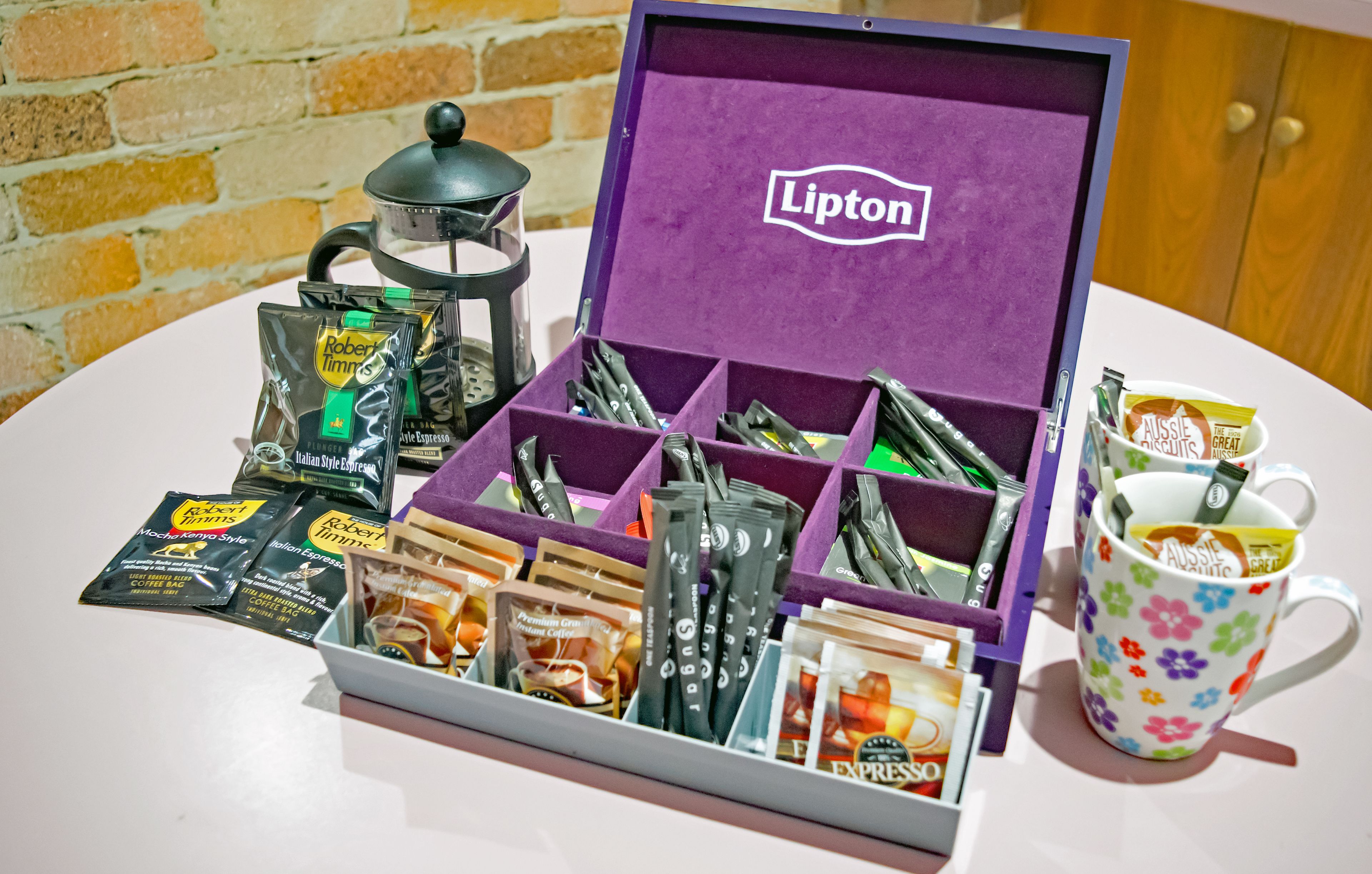 Un set de regalo de café que incluye té Lipton, cápsulas de café variadas y una taza con motivos florales.