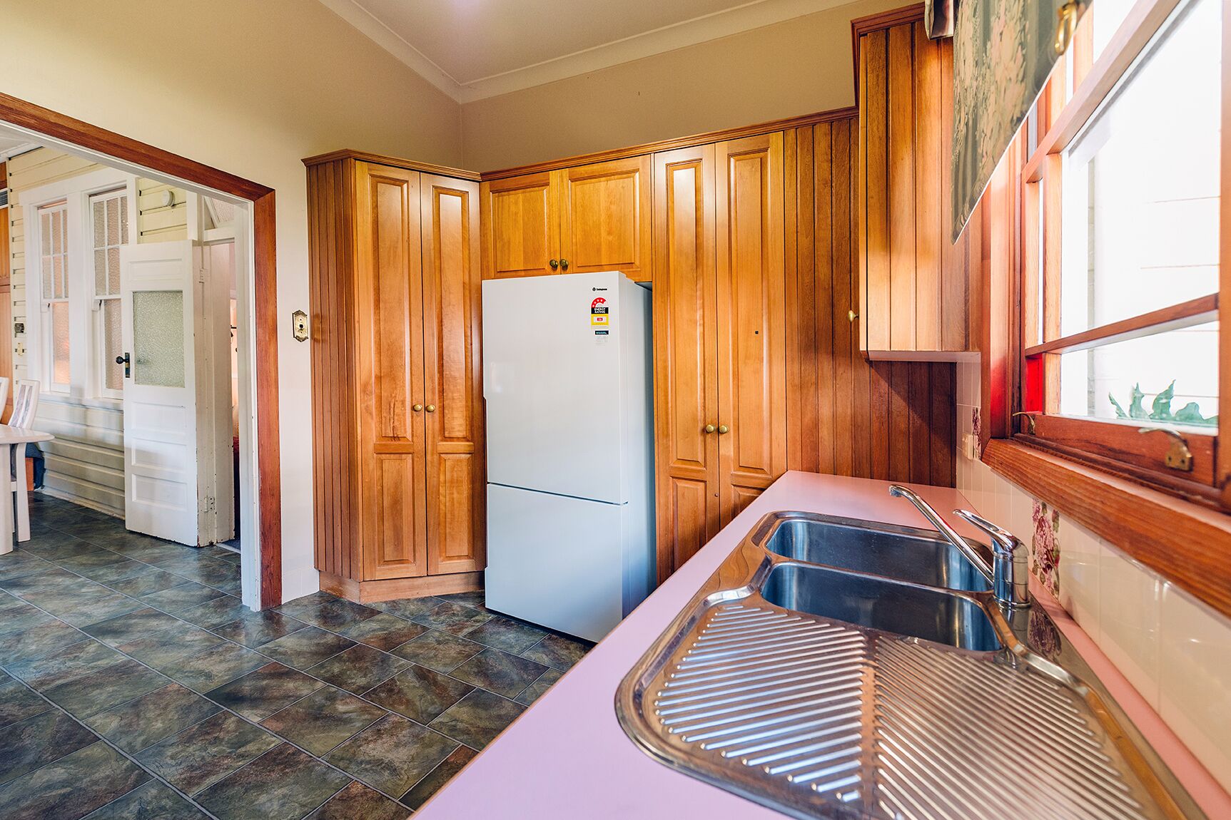 A kitchen with wooden cabinets, a white refrigerator, and a stainless steel sink.