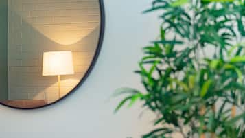 A round mirror reflecting a brick wall and a wall-mounted lamp.